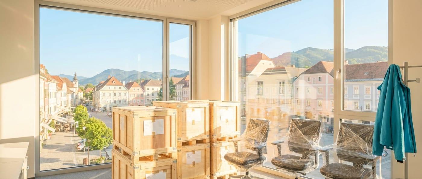 Verpackte Büroausstattung am Abend vor der Fensterfront — Büroumzug außerhalb der Geschäftszeiten