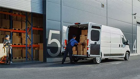 Mann räumt Kisten in einen Transporter