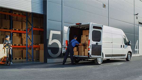 Mann räumt Kisten in einen Transporter